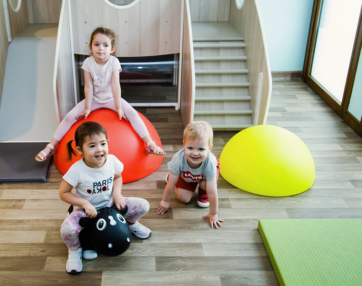 Three children play on space hoppers in a Grandir nursery